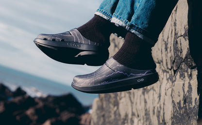 Person wearing Usal x OOFOS Cochno Clog with a mountainous background | lifestyle