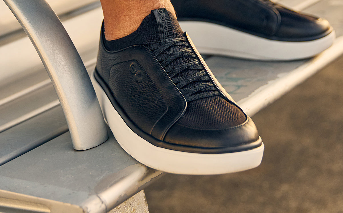 Black sneakers with white soles on a metal surface