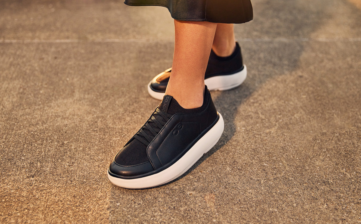 Black sneaker with white sole worn on a textured surface | lifestyle