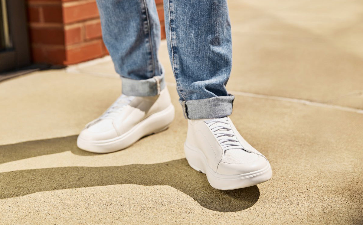 White sneakers worn with blue jeans on a concrete surface | lifestyle