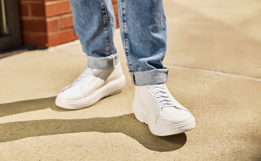 White sneakers worn with blue jeans on a concrete surface | lifestyle