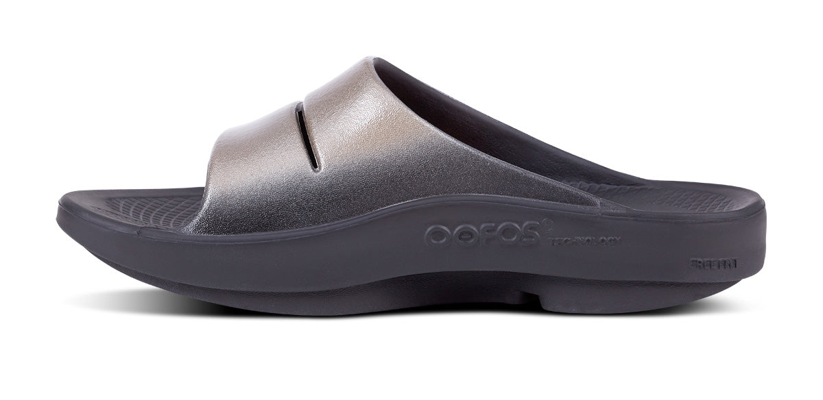 Women's OOahh Luxe Slide Sandal - Latte - OOFOS lifestyle image of model walking in shoes