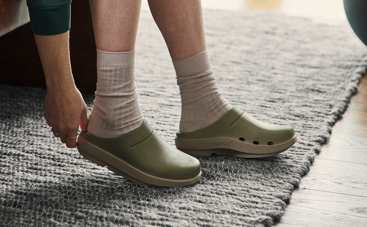 Women's OOcloog Luxe Clog - Foliage model sitting adjusting shoe inside | lifestyle