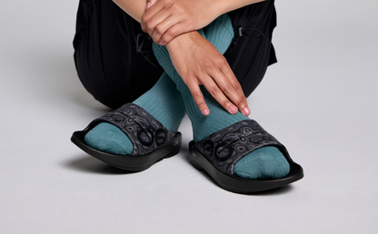 Women's OOahh Sport Slide Sandal - Black Water Camo model in shoes sitting on studio floor | lifestyle