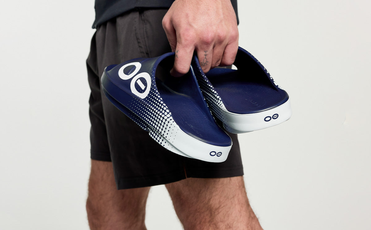 Men's OOahh Sport Slide Sandal - Navy Matrix model holding shoes in studio | lifestyle