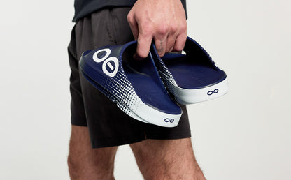 Men's OOahh Sport Slide Sandal - Navy Matrix model holding shoes in studio | lifestyle