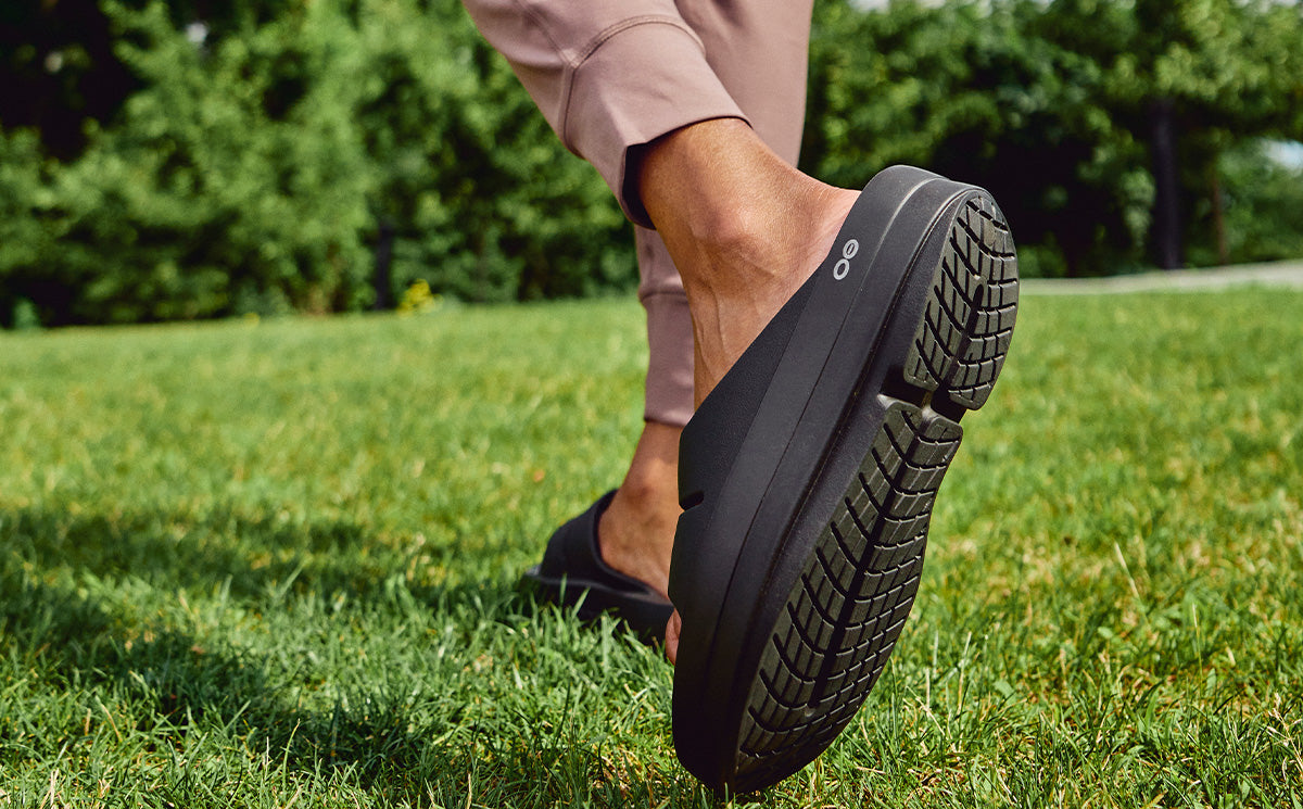 Women's OOmega OOahh Sandal - Black lifestyle close up image of shoe on model outside | lifestyle