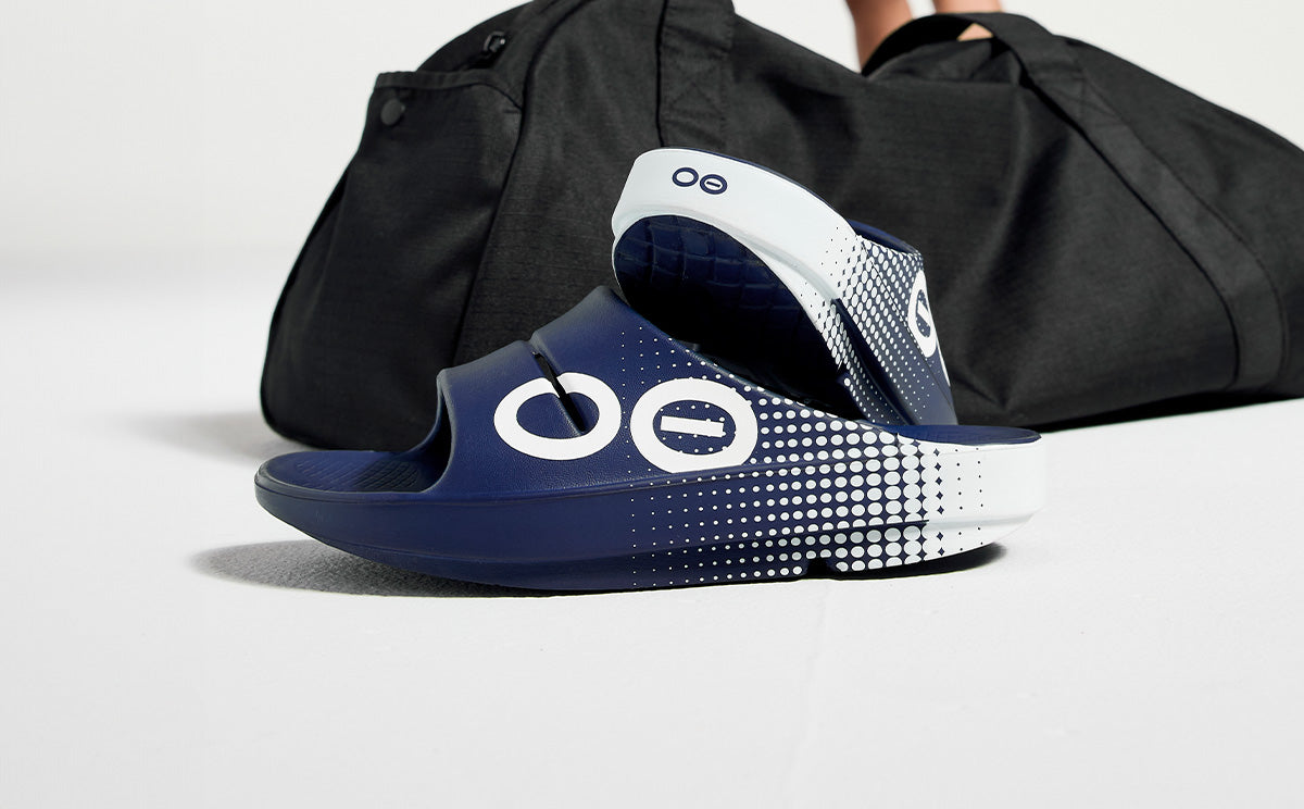 Women's OOahh Sport Slide Sandal - Navy Matrix shoes in studio in front of gym bag | lifestyle