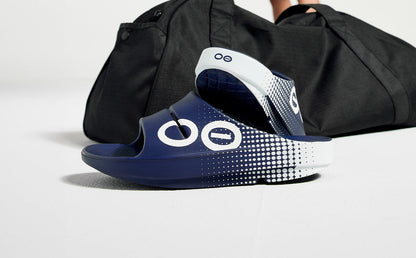 Women's OOahh Sport Slide Sandal - Navy Matrix shoes in studio in front of gym bag | lifestyle