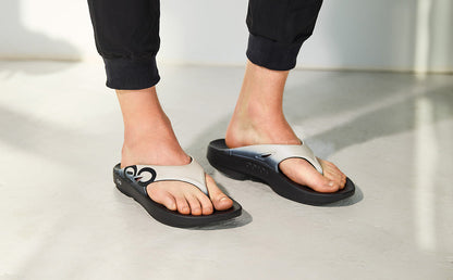 Person wearing black sandals on a light gray floor | lifestyle