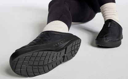 Women's OOcoozie Thermo Mule - Black close up of shoes on model sitting in studio | lifestyle