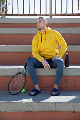 Men's OOahh Sport Slide Sandal - Navy White model wearing shoes sitting on stairs with tennis racket