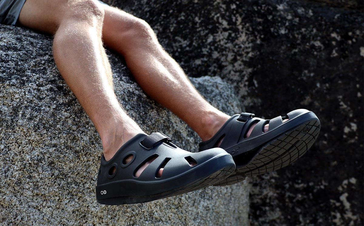 Men's OOcandoo Sandal - Black model in shoes sitting on rock