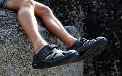 Men's OOcandoo Sandal - Black model in shoes sitting on rock