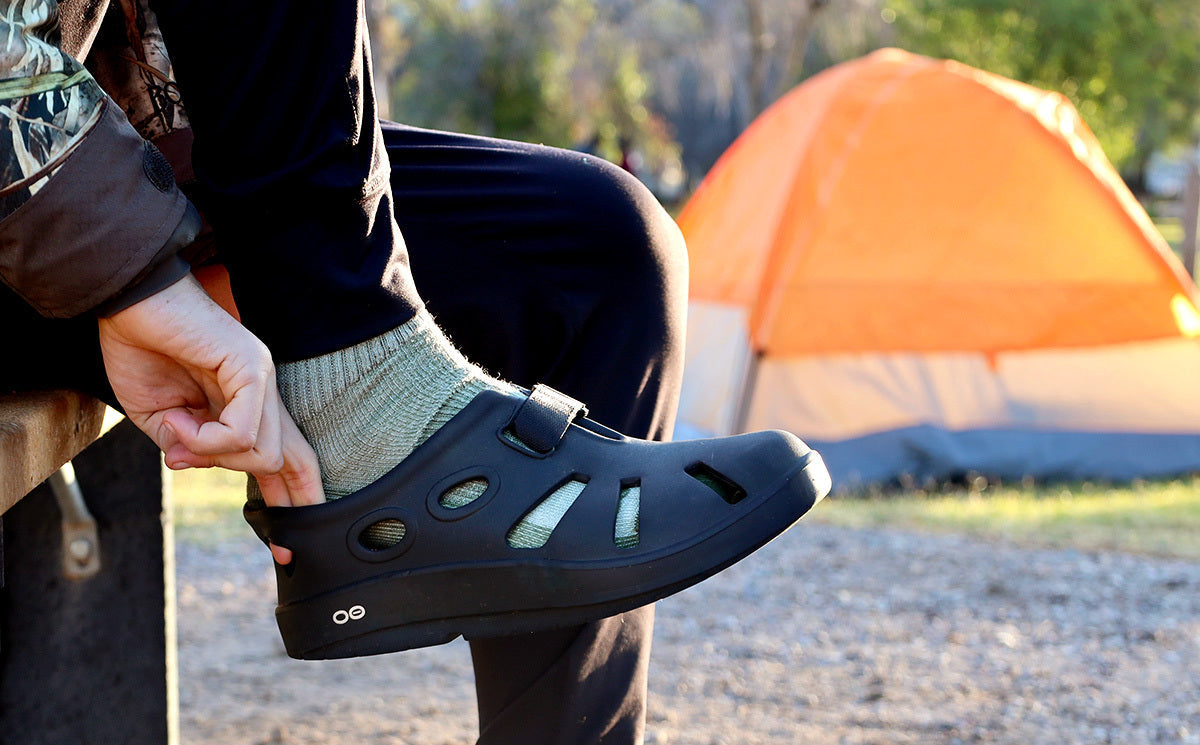 Men's OOcandoo Sandal - Black model putting on shoe