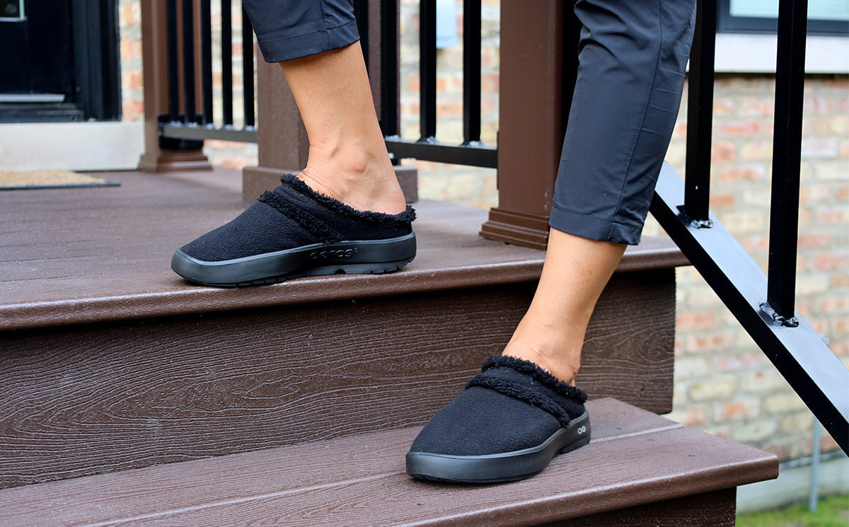 Women's OOcoozie Mule Shoe - Black model in shoe on stairs